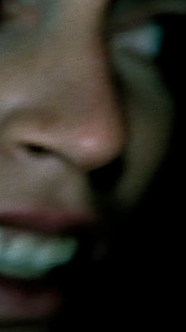 A blurry female face gritting her teeth